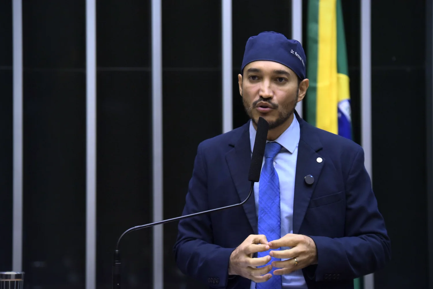 Dr. Fernando Máximo discursando na tribuna da Câmara dos Deputados, com a bandeira do Brasil ao fundo